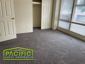 Medford apartment for rent - a carpeted living room with a door and a pacific rental property logo on