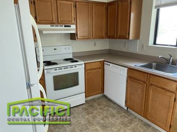 Ashland apartment for rent - a small kitchen with white appliances and wooden cabinets