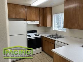 Ashland apartment for rent - a small kitchen with white appliances and wooden cabinets