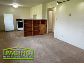 Ashland apartment for rent - an empty living room with a refrigerator and a book shelf