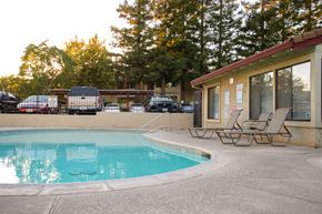 Chico apartment for rent - A pool with chairs and a building in the background.