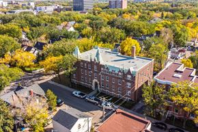 Regina apartment for rent - A large red brick building with a green roof sits in the middle of a street.