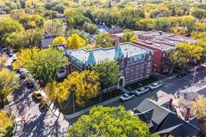 Regina apartment for rent - A large building with a green roof is surrounded by trees with yellow leaves.