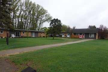 Watrous condo for rent - A grassy area in front of a building with a red sign on it.