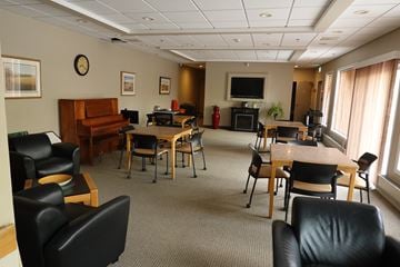 Regina apartment for rent - A conference room with a piano, chairs, and a television.