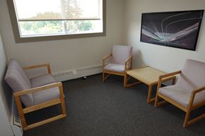Regina apartment for rent - A room with a grey carpet and a painting on the wall.