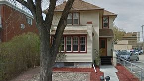 Regina apartment for rent - A house with a red brick wall and a tree in front.