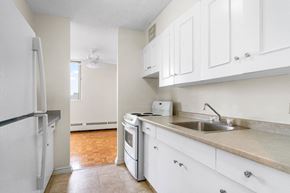 Regina apartment for rent - A kitchen with white cabinets and a white fridge.