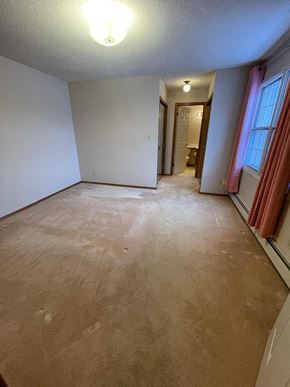 Regina condo for rent - A room with a carpeted floor and a doorway leading to another room.