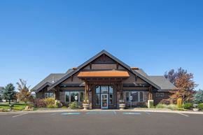 Spokane apartment for rent - A building with a brown roof and glass windows and a parking lot in front.