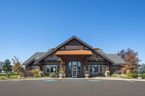 Spokane apartment for rent - A building with a brown roof and glass windows and a parking lot in front.