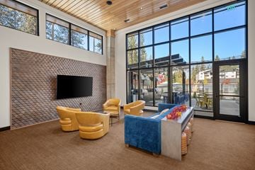 Spokane apartment for rent - A living room with a television, chairs, and a table with a vase of flowers.