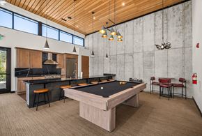 Coeur D'alene apartment for rent - A billiards table is in the middle of a room with a bar and a kitchen.