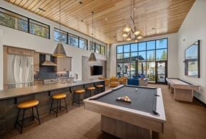 Spokane apartment for rent - A billiard table is in the middle of a room with a kitchen area and a balcony.