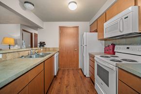 Spokane apartment for rent - a kitchen with white appliances and wooden cabinets and a white refrigerator