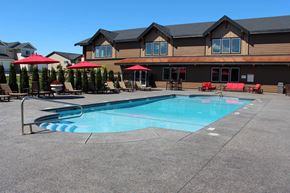 Spokane apartment for rent - a swimming pool in front of a hotel with chairs and umbrellas
