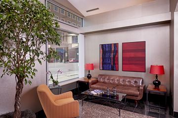 Minneapolis apartment for rent - A living room with a brown couch, a tree, and two paintings on the wall.