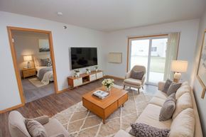 Fargo apartment for rent - A living room with a large couch, a coffee table, and a flat-screen TV.