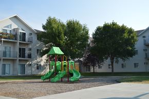 Fargo apartment for rent - A playground with a green slide in front of apartment buildings.