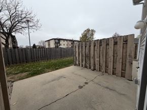 Fargo apartment for rent - A wooden fence separates a driveway from a grassy area.