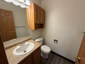 Fargo apartment for rent - A bathroom with a toilet, sink, and mirror.