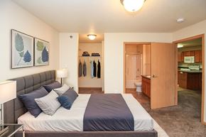 Fargo apartment for rent - A bedroom with a bed, a lamp, and a coat rack.