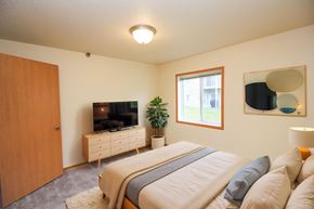 Fargo apartment for rent - A bedroom with a large bed and a flat screen TV mounted on the wall.