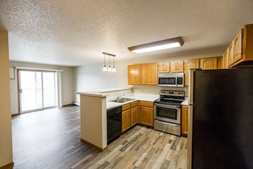Bismarck apartment for rent - A kitchen with wooden cabinets and a black refrigerator.