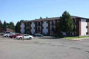 Bismarck apartment for rent - A parking lot with cars and a building in the background.
