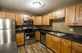 Bismarck apartment for rent - A kitchen with wooden cabinets and a stainless steel refrigerator.