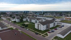 Fargo apartment for rent - A parking lot with cars and a white building in the background.