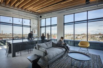 Minneapolis apartment for rent - a man sitting on a couch in a living room with a view of the city