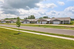 Wyoming apartment for rent - A tree stands alone in a grassy field in front of a row of houses.