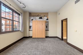 Grand Rapids apartment for rent - A room with a wooden wardrobe and a window overlooking a building.