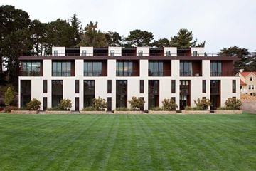 San Francisco triplex for rent - A large white building with black trim and windows sits on a lush green lawn.