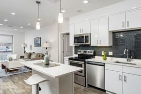 Cambridge apartment for rent - an open kitchen and living room with white cabinets and stainless steel appliances