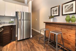 Boston apartment for rent - a kitchen with a stainless steel refrigerator and a bar with stools