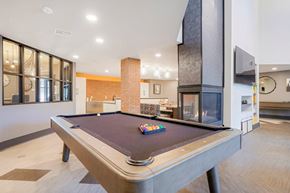 Colorado Springs apartment for rent - A pool table in a room with a brick wall and a fireplace.