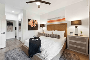 Scottsdale apartment for rent - A bedroom with a large bed, a ceiling fan, and a painting on the wall.