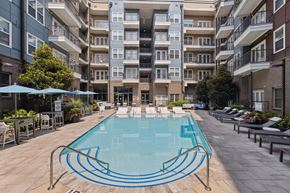 Charlotte apartment for rent - an outdoor swimming pool with lounge chairs and umbrellas in front of an apartment building