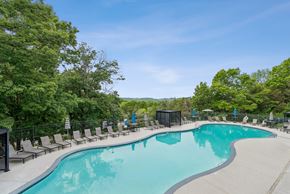 Nashville apartment for rent - A large outdoor swimming pool surrounded by trees and lounge chairs.