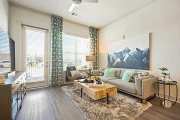 Centennial apartment for rent - A living room with a grey couch and a large mountain painting on the wall.