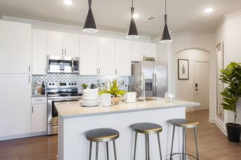 Sleek quartz countertops with designer tile backsplash and cabinetry