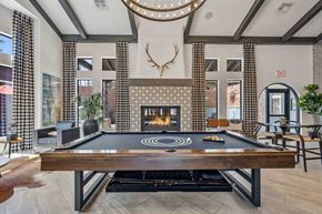 Chandler apartment for rent - A pool table is in the middle of a room with a fireplace and a deer head mounted on the wall.