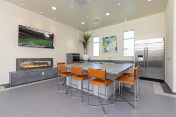 Henderson apartment for rent - A modern kitchen with a fireplace and a dining table with orange chairs.