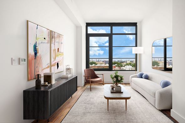 Queens apartment for rent - A living room with a large window, a brown chair, a white couch, and a painting on the wall.