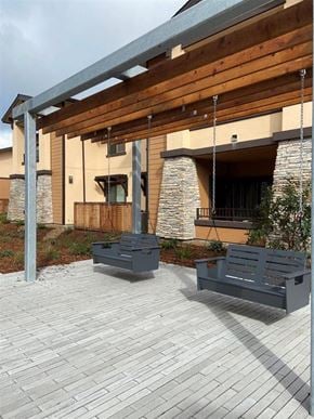 Santa Rosa apartment for rent - Two grey benches are placed on a patio in front of a building.