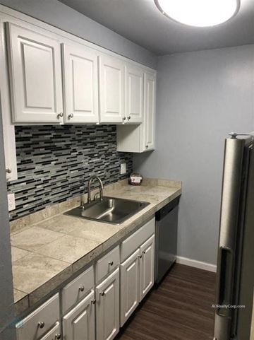 Reno apartment for rent - A kitchen with white cabinets and a stone backsplash.