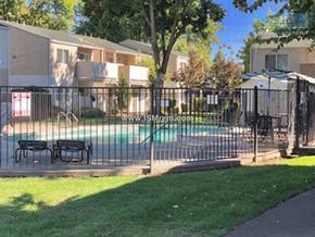 Chico apartment for rent - A pool surrounded by a black fence in a grassy area.