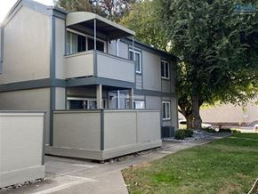 Chico apartment for rent - A grey apartment building with a tree in front.
